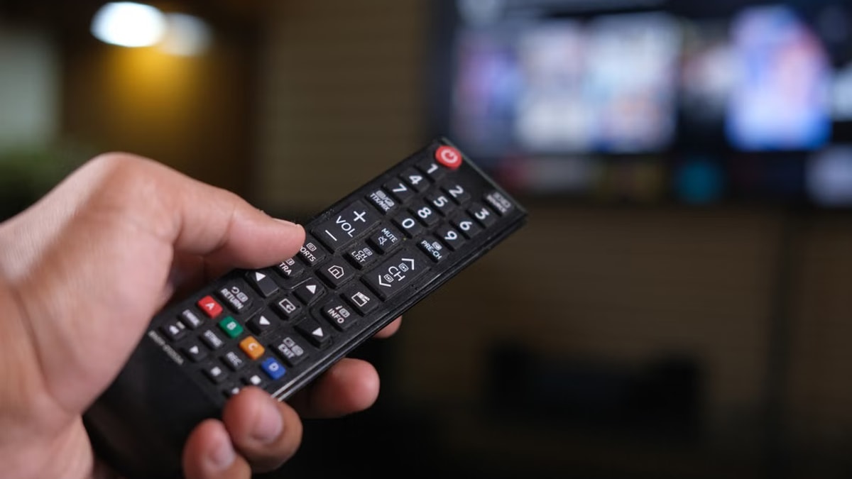 TV 화면을 향해 리모컨을 들고 있는 모습